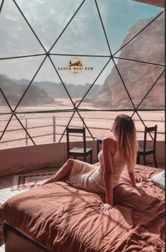 Eine Frau, die auf einem Bett vor einem Fenster sitzt. in der Unterkunft SADEM WADl RUM in Wadi Rum