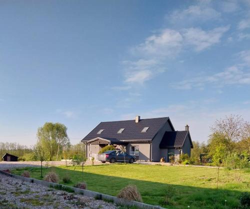 a house with a car parked in front of it at Dolina dwóch stawów in Piorkowo