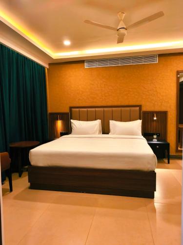 a bedroom with a large bed with a ceiling fan at Parays Fernwoods in Mannārakkāt