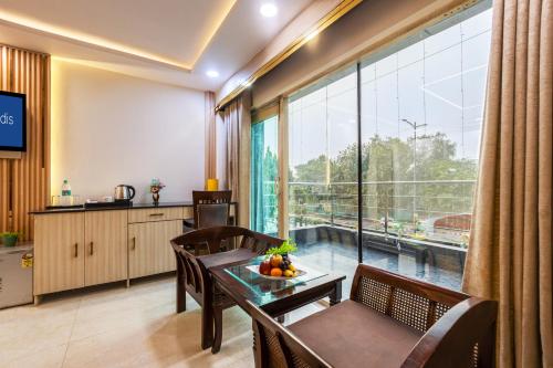 uma sala de jantar com uma mesa e uma grande janela em Hotel Downtown - East of Kailash em Nova Deli