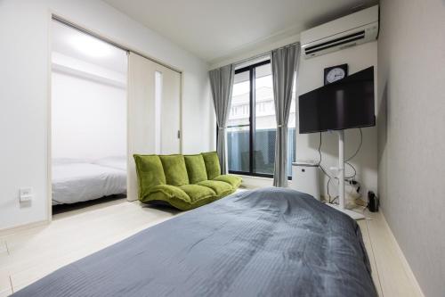 a bedroom with a bed and a green chair at Villetta Imari Ekimae III Room 103 - Vacation STAY 19026 in Imari