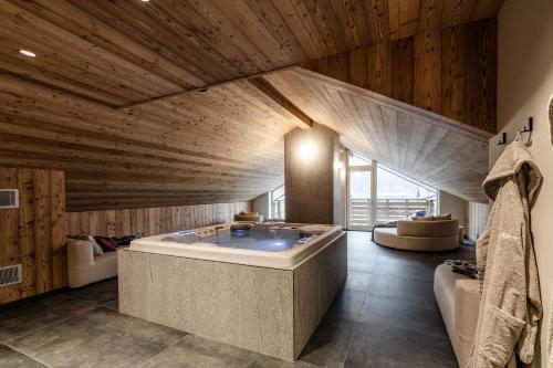 a large room with a tub in a room with wooden ceilings at El Giof Alpine Home in Pellizzano