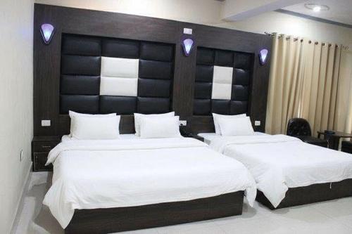 1 dormitorio con 2 camas y cabecero grande en Hotel Samar, en Srinagar