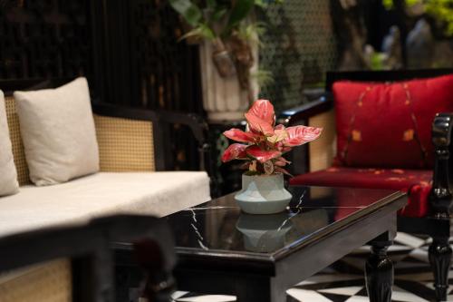 a living room with a table with a vase with flowers on it at C'Lau Hotel Ninh Binh in Ninh Binh