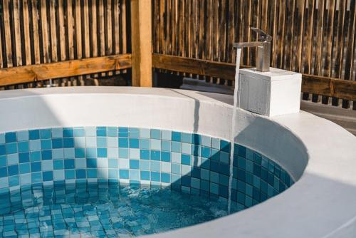a bathroom with a tub with a sink and a faucet at Jeju Mureungri The house in Murŭng-ni