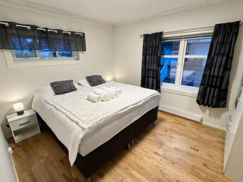 een slaapkamer met een bed en twee ramen bij Spacious apartment in a quiet area in Narvik