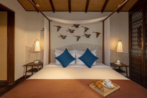 a bedroom with a bed with birds on the wall at Little Oasis - An Eco Friendly Hotel & Spa in Hoi An