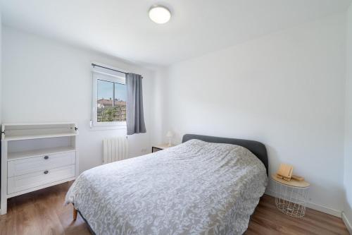 ein weißes Schlafzimmer mit einem Bett und einem Fenster in der Unterkunft Chez Adrien au Haillan Appt rez de chaussée jardin in Le Haillan
