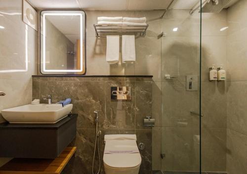 a bathroom with a toilet and a sink and a shower at Olwen Suites in Cochin