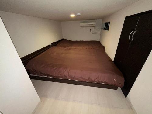a small bedroom with a bed in a small room at Guest House Ogusu INN in Fukuoka