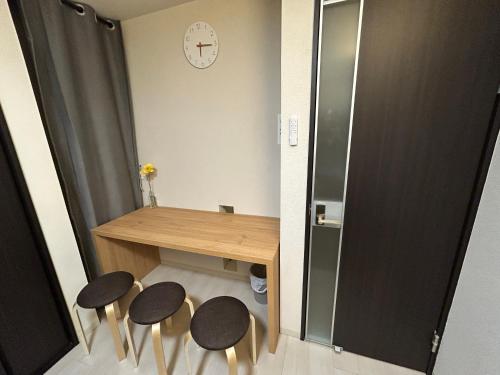 a room with a wooden table and four stools at Guest House Ogusu INN in Fukuoka