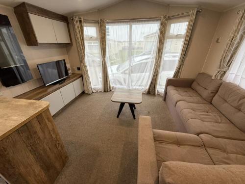 ein Wohnzimmer mit Sofa und Fernseher in der Unterkunft Oscars Inn, West Sands, Seal Bay Resort in Selsey
