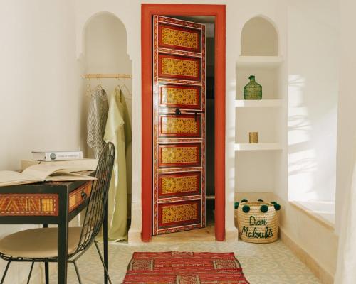 - une porte dans une chambre avec une table et un bureau dans l'établissement Riad dar Maloukti, à Marrakech