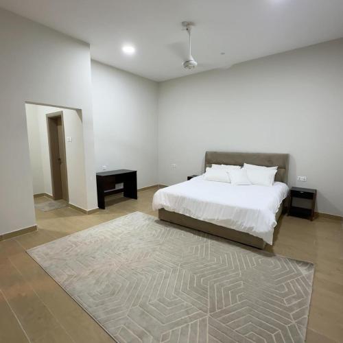 a white bedroom with a bed and a rug at Alhana Oasis in Badīyah