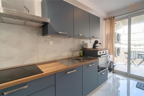 a kitchen with blue cabinets and a sink at Seaside Comfort in St'Pauls Bay steps from the Sea by 360 Estates in St Paul's Bay