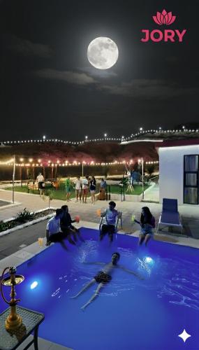 eine Gruppe von Menschen, die nachts am Pool sitzen in der Unterkunft شاليه منتجع جوري حتا الخاص -J3- Jory Hatta Private Resort Chalet in Hatta