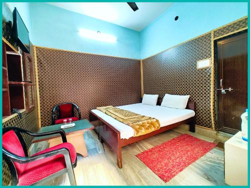 a small bedroom with a bed and a chair at Hotel Shilpa Teerth Palace Guest House Near Vishwanath Temple - #Fully Air Conditioned Rooms #Restaurant And Wi-fi Facility - Best Prmium Hotel In Varanasi in Kashi