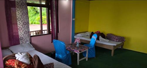a room with two beds and a table with chairs at Brookland Stays in Pedong