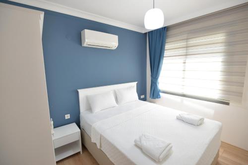 a bedroom with a white bed and a blue wall at Arti̇m Apart Hotel in Fethiye