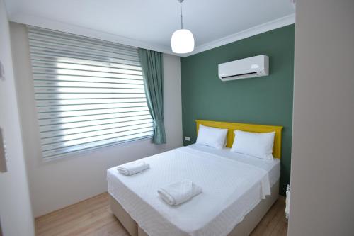 a bedroom with a bed with white sheets and a window at Arti̇m Apart Hotel in Fethiye