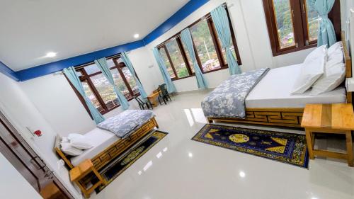a bedroom with two beds in a room with windows at Naku homes in Dirang Dzong