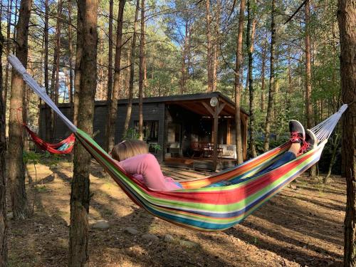 a woman laying in a hammock in the woods at Lukasowy domek w Puszczy Noteckiej in Biala