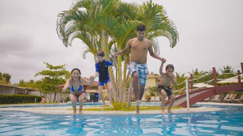 a man and two children playing in a swimming pool at Casa Andina Select Zorritos Tumbes in Zorritos