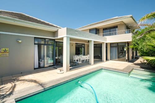 une maison avec une piscine devant une maison dans l'établissement Belina - Sunset Links Golf Course Villa, au Cap
