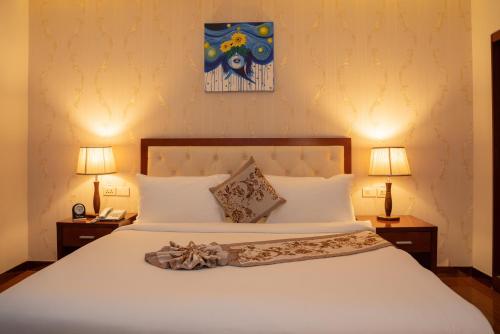 a bedroom with a large white bed with two lamps at Tolip Olympia Hotel in Addis Ababa