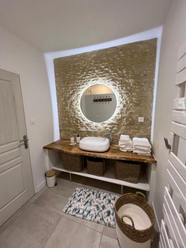 ein Badezimmer mit Waschbecken und Spiegel in der Unterkunft Charmante maison du XVIII en pierre rénovée in Colleville-Montgomery