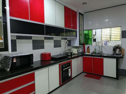 a kitchen with red and white cabinets and appliances at 主人房玻璃市港口 in Kuala Perlis