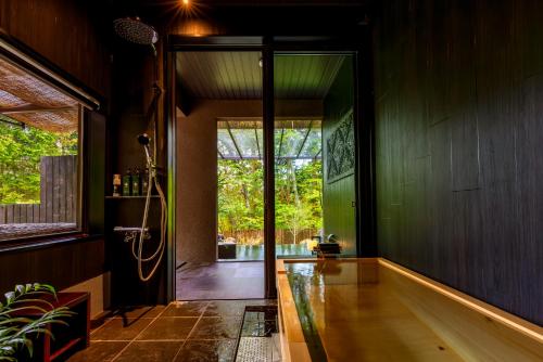 a bathroom with a tub and a glass door at 箱根懐來 in Hakone