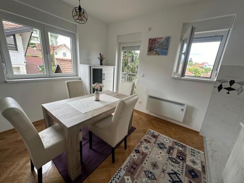 a dining room with a table and chairs and windows at studio apartman elegant in Vrnjci