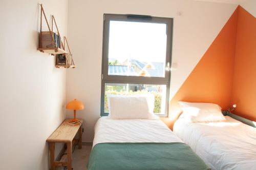 two beds in a room with a window at Duplex 6 personnes, vue panoramique sur lac in Malbuisson