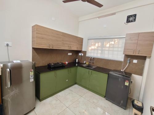 a kitchen with green cabinets and a stainless steel refrigerator at 88 GREEN FORT EDAPALLy in Ernakulam