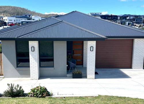 a house with a metal roof and a garage at Green Hill Views - Family Home close to Hobart in Rokeby