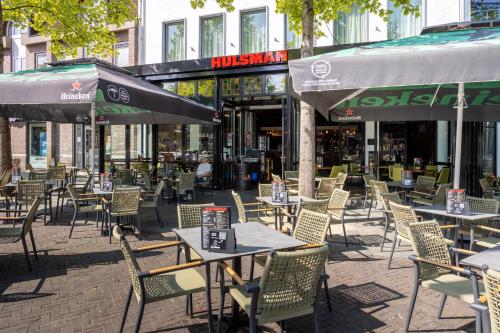 an outdoor restaurant with tables and chairs and umbrellas at Hotel Hulsman in Venray