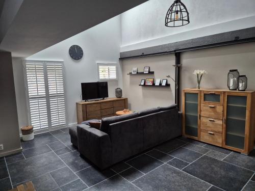 a living room with a couch and a tv at Gastenverblijf Oesj in Eijsden