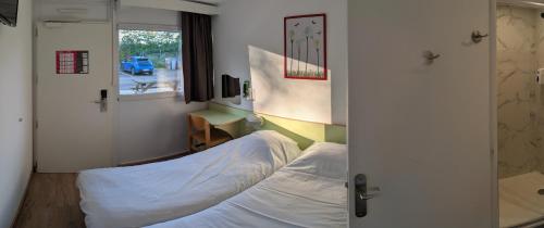 Un dormitorio con una cama y un escritorio y una ventana. en Fasthotel Well Inn Mâcon sud - un hôtel FH Confort, en Charnay-lès-Mâcon