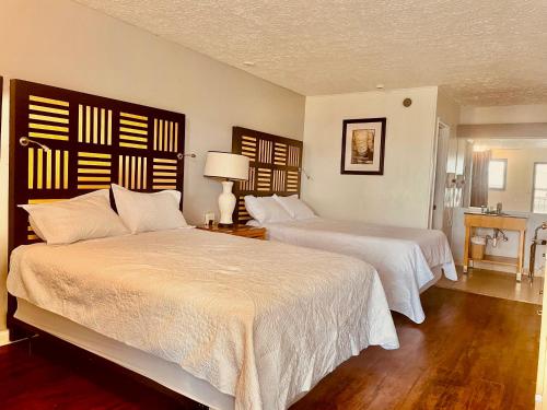 a bedroom with two beds with white sheets and a table at Motel M Lewisburg in Lewisburg