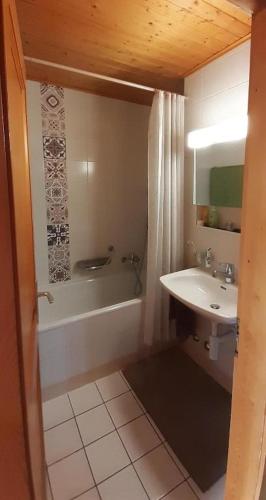 a bathroom with a sink and a tub and a toilet and a sink at Narcisse 15 in Champoussin