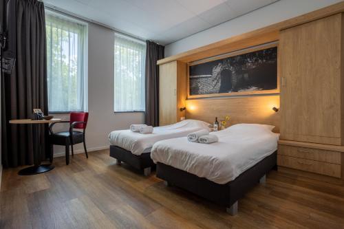 a hotel room with two beds and a desk at Hotel Hulsman in Venray
