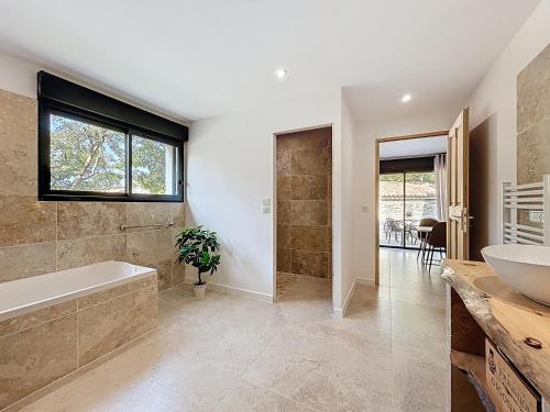 un bagno con vasca, lavandino e finestra di La villa dans les arbres - Triangle d'or du Luberon a Ménerbes