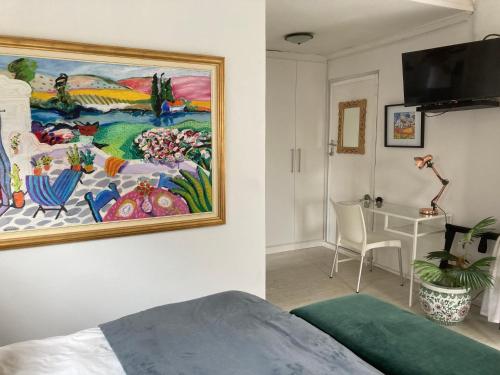 a bedroom with a painting hanging on the wall at Constantia Lazy River in Cape Town