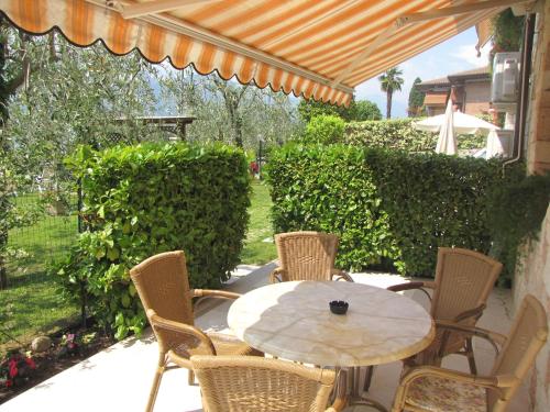 a table and chairs on a patio with an umbrella at Residence Villa Margherita in Brenzone sul Garda