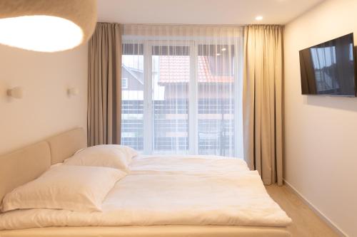 een bed in een kamer met een groot raam bij Wave 21 Nida Self Check-In Apartment in Nida