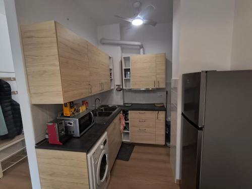 Una cocina con gabinetes de madera y un refrigerador de acero inoxidable. en Bagaini Urban Flat, en Varese