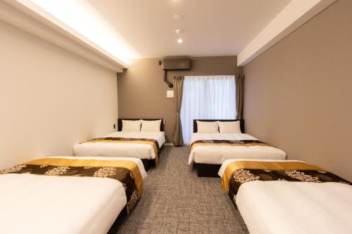 a row of beds in a room with a window at Tabi and -light- Hakata01 in Fukuoka