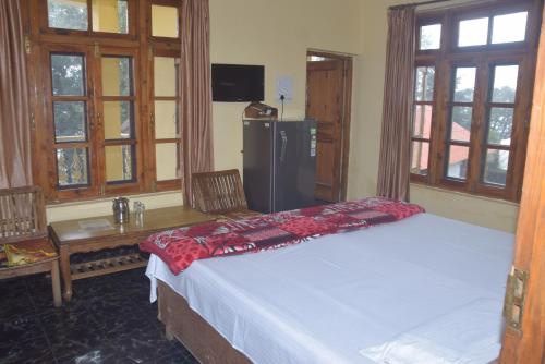 een kamer met een bed, een koelkast en ramen bij Sahil cottage in Chamba