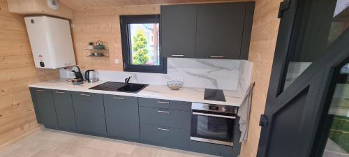 a kitchen with gray cabinets and a sink and a window at Gîtes des Deux Sapins 